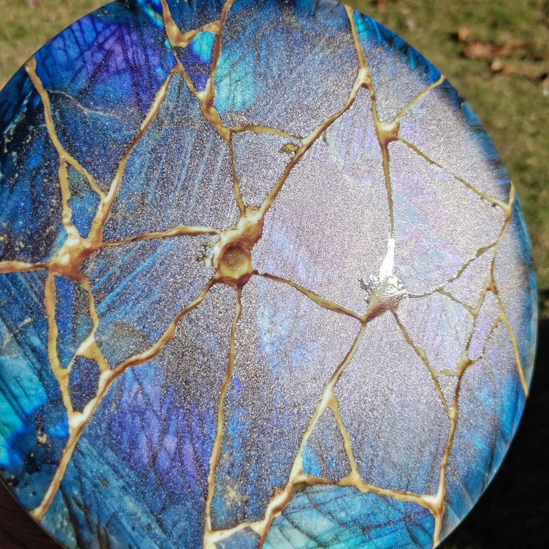 Kintsugi disc held in direct sun with the gloss gold veins catching the light