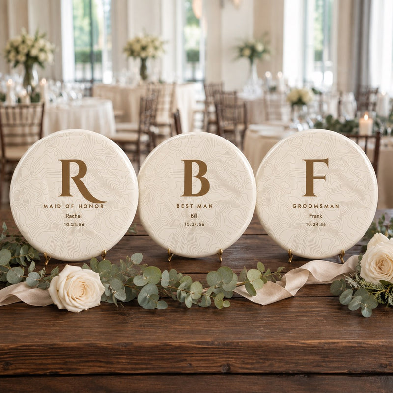 Three personalized wedding party disc golf discs - maid of honor, best man and groomsman - on a reception table