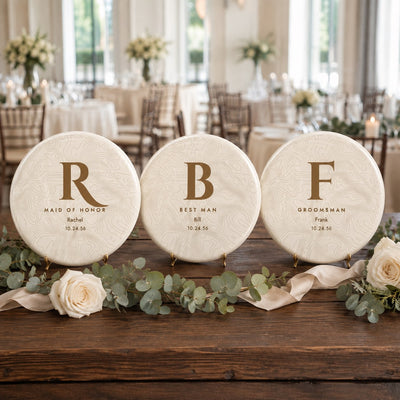 Three personalized wedding party disc golf discs - maid of honor, best man and groomsman - on a reception table
